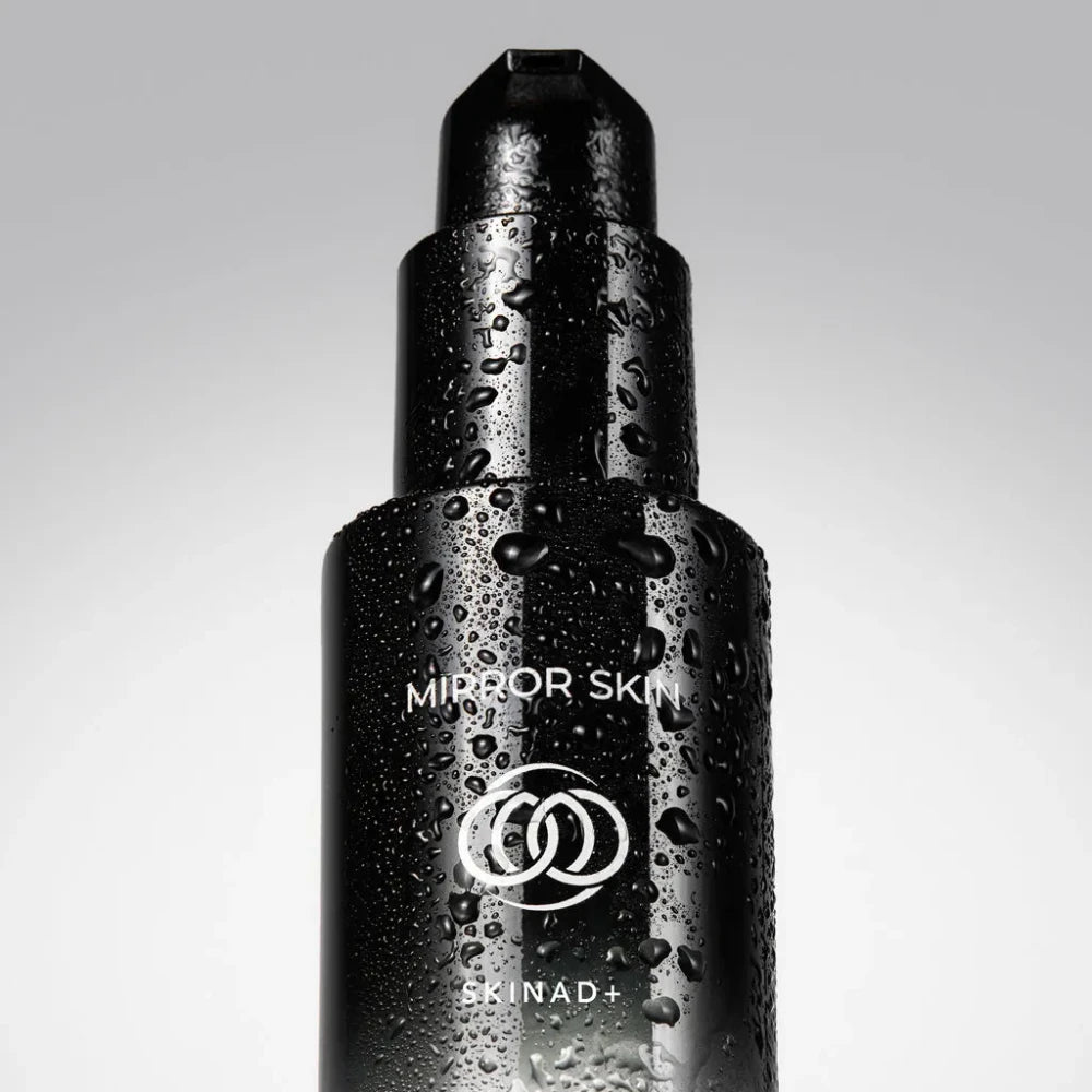Black skincare bottle with 'Mirror Skin' and 'SKINAD+' branding on a gray background